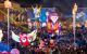 Brightly-illuminated carnival float surrounded by crowds