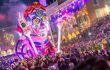 Brightly-illuminated carnival float surrounded by crowds