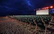 Empty green film festival deck chairs lined up in front of an outdoor cinema screen