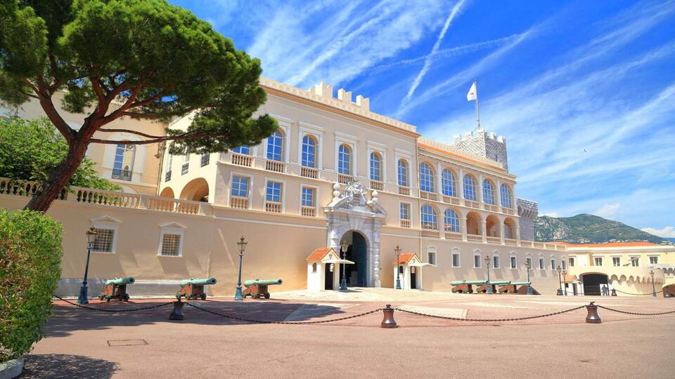 Grand, cream-coloured palace's front entrance courtyard on a sunny day