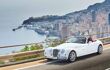 White convertible driving on a cliff-side highway looking down over Monaco