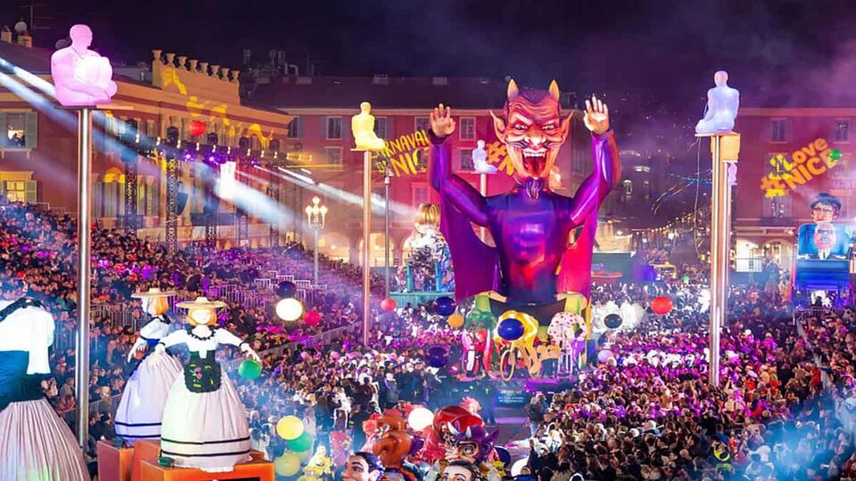 Carnival float of a large devil at night in front of crowds