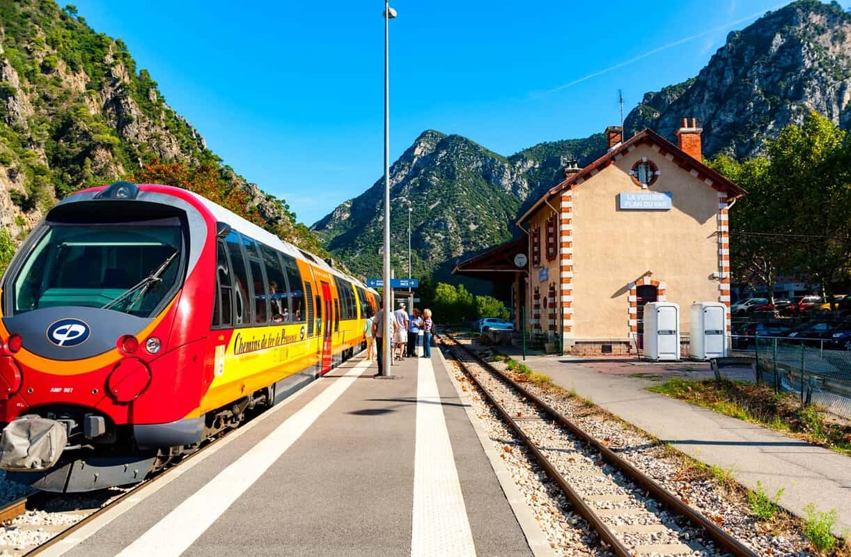 Small railway platform in a valley with a red train