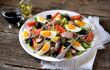 French salad Nicoise with tuna, boiled potatoes, egg, green beans, tomatoes, dried olives, lettuce and anchovies.