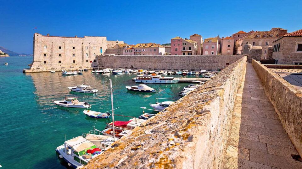 Historic city walls walk and Saint Ivan fortress in Dubrovnik harbor view