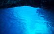 Inside the dark cave with bright blue illuminated water