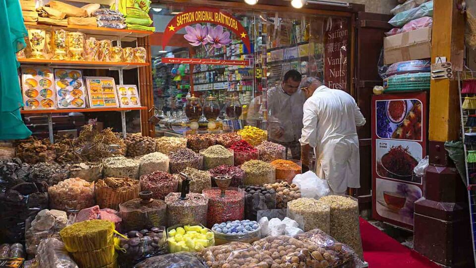 Merchant selling spices to client in Dubai spice souk in Deira district. Traditional spices shop in old town
