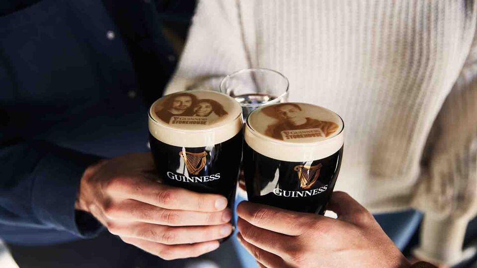 man holsing two pints of guinness in the inside the Guinness Storehouse experience