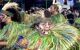 A parade performer dressed in a costume smiles at the camera