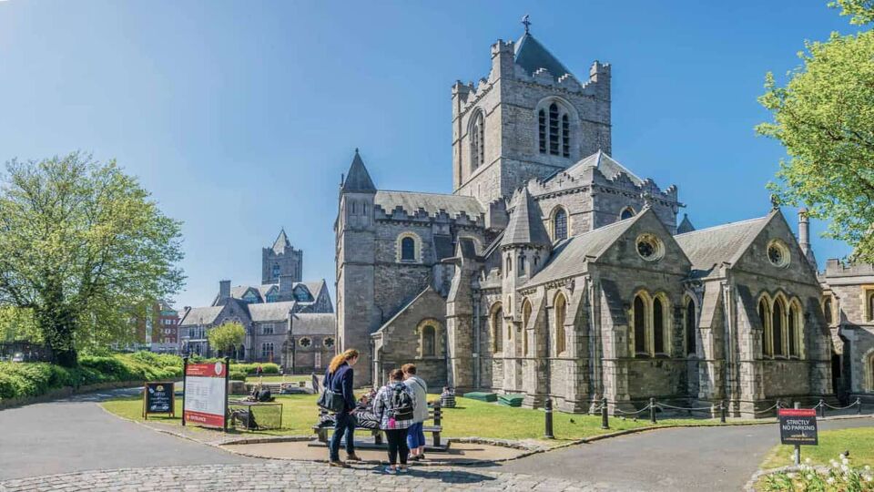 People sitting in front of the Christ church Cathedral in the sunshine