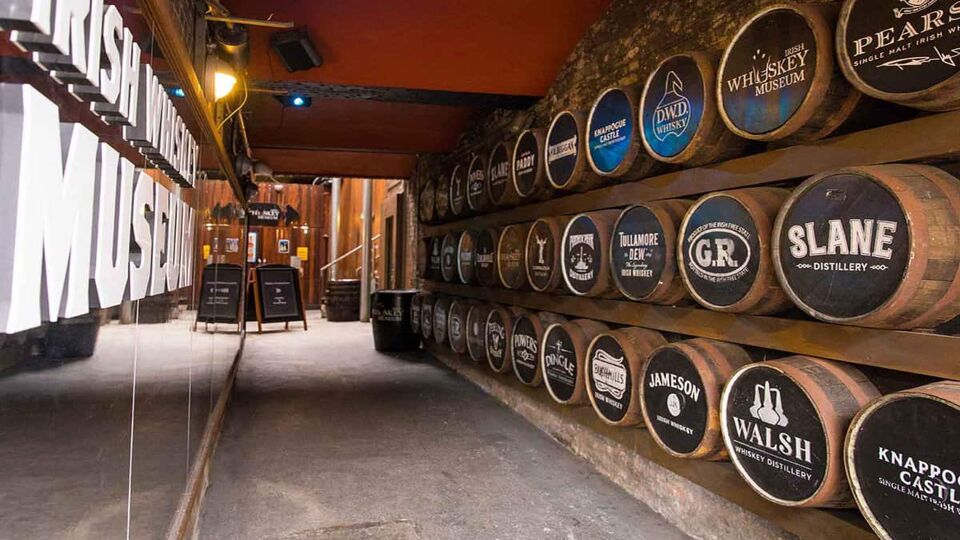 Entry hall to the museum with a wall of whisky barrels on one side with different brands on