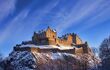 Edinburgh castle dusted with snow glows in the late afternoon winter sunset.