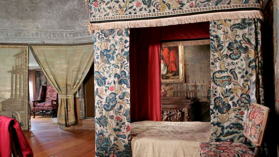 old fashioned bedroom with four-poster bed surrounded by heavy drapes
