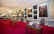 long hallway with red carpet and paintings on the wall
