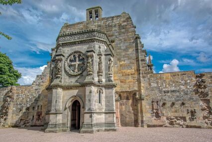 A low angle of the entrance and front facade of Rosslyn Chapel, a small stone building