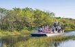 group of international tourists riding an airboat. The Everglades are a natural region of wetlands in the southern portion of the U.S. state of Florida.