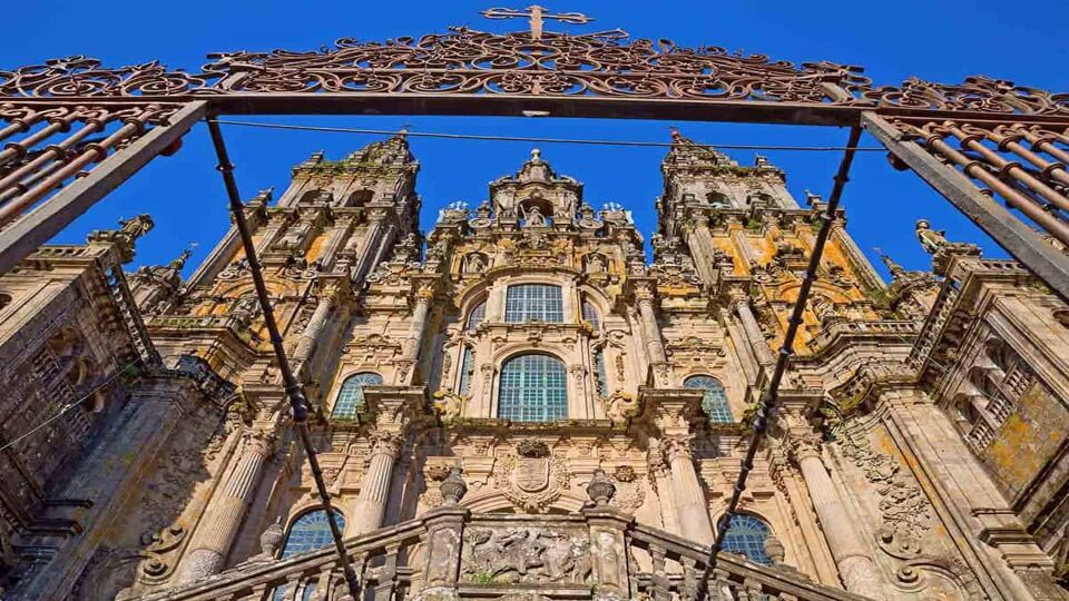Facade of Cathedral of Santiago de Compostela with blue sky and grille
