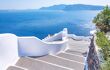 Traditional narrow street with stairs leading to the sea in Oia village, Santorini Island, Greece. Beautiful summer landscape, sea view