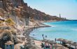 People swimming and sunbathing at beach near white rocks of Vlychada town of Santorini island, Greece