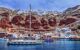 Sailing yacht and boats near the harbor of Oia, Santorini island, Greece. View on red rocks caldera and white houses in the sky