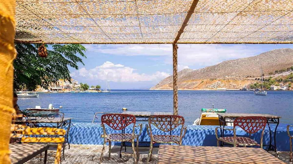 Panoramic view of small haven of Symi island. Village with Street Cafe and colorful houses located on rock.