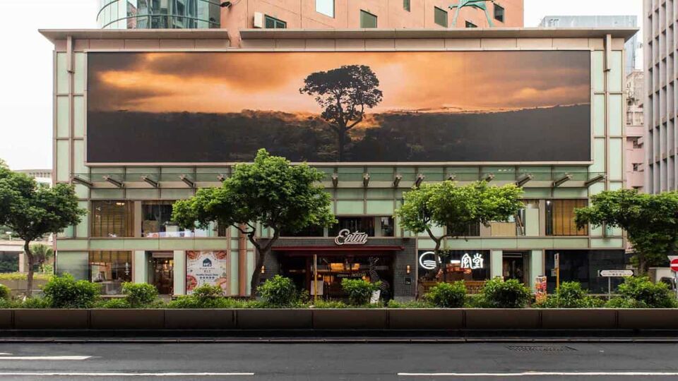 Front of the hotel with trees and a large scenic poster on glass panels