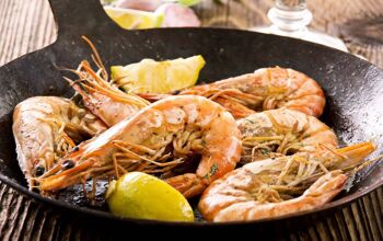 Iron wok with whole prawns being cooked inside