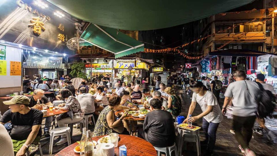 Tourists and locals crowded around tables in a busy area of the night market
