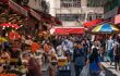 A bustling street food market where people are buying groceries