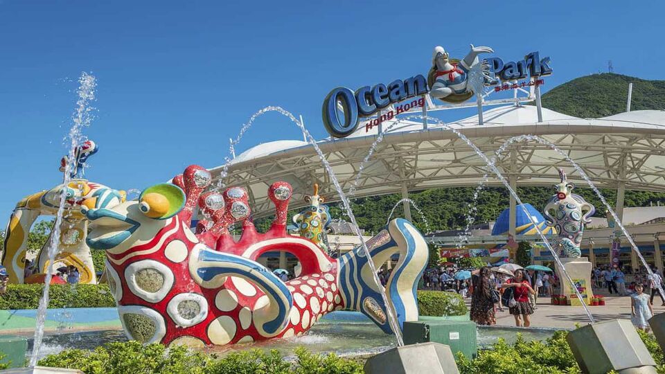 Sculpted, colourful fish fountains with the Ocean Park building in the background and a blue sky above