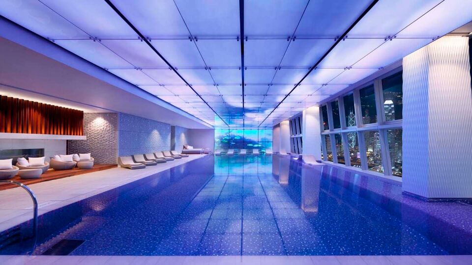 Indoor swimming pool at night with futuristic lighting and lounge beds