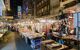 Rows of vendors selling their products as people walk through the market