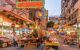 Street food vendors and merchants selling their products set up in rows, illuminated by neon glowing signs