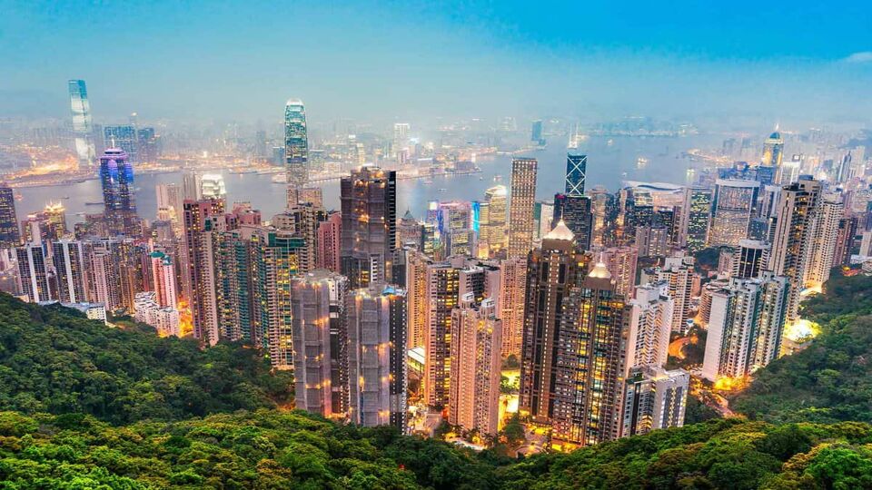 The dazzling skyline lit up at twilight set against the lush greenery of the peak
