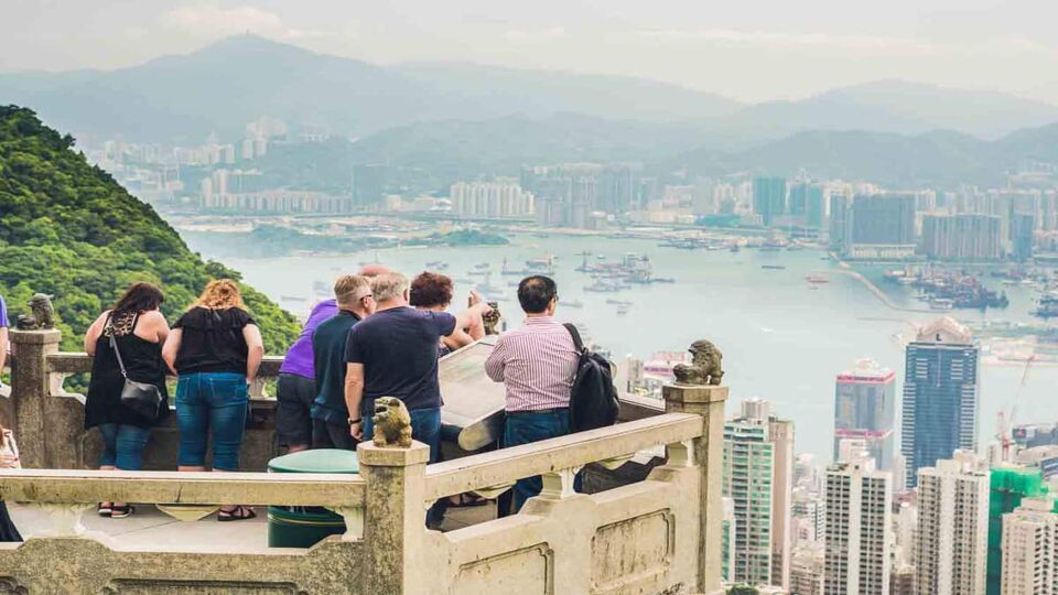 Tourists packed together on the Lion's Pavilion to admire the view of the buildings and harbour down below