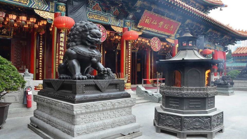 Black lion statue next to a flaming altar in front of the temple