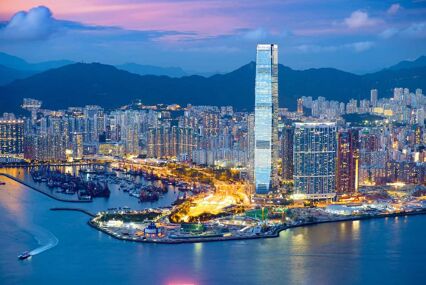 Beautiful aerial view of West Kowloon and the bay at sunset, with a glittering skyscraper poking up towards the sky