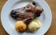 cooked sheep's head on a plate with potatoes