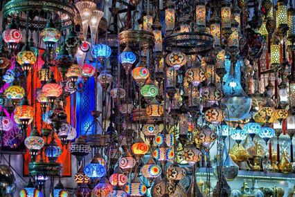 Intricate, illuminated Turkish lamps hanging from the ceiling inside a market