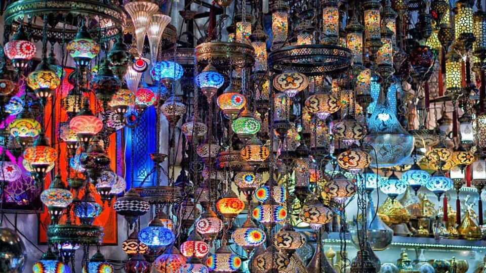 Intricate, illuminated Turkish lamps hanging from the ceiling inside a market