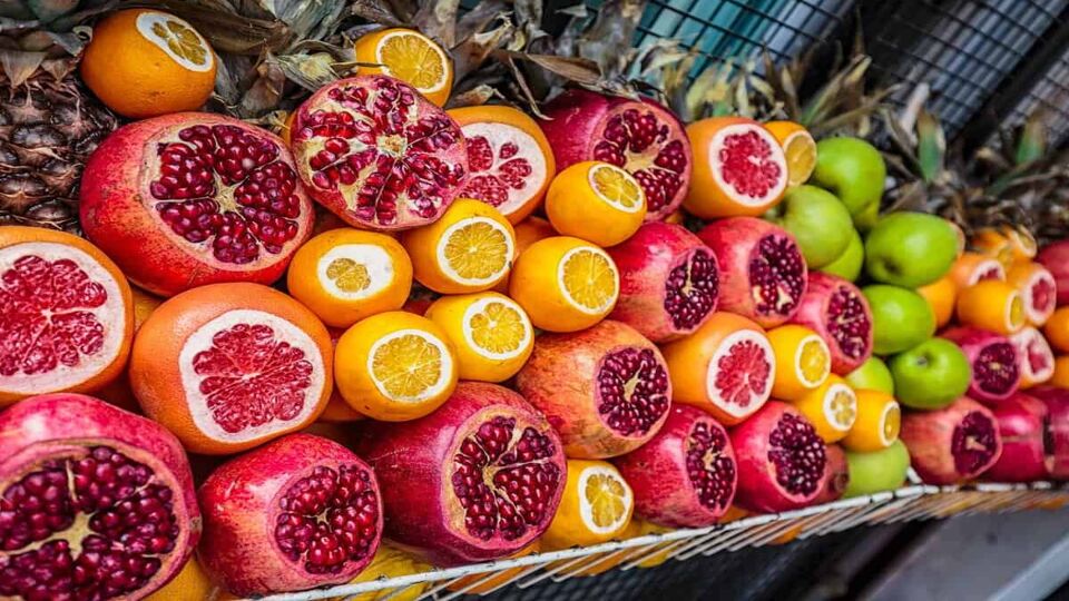 Close-up of pomegranates, oranges and grapefruits sliced in half and on display in front of a market stall