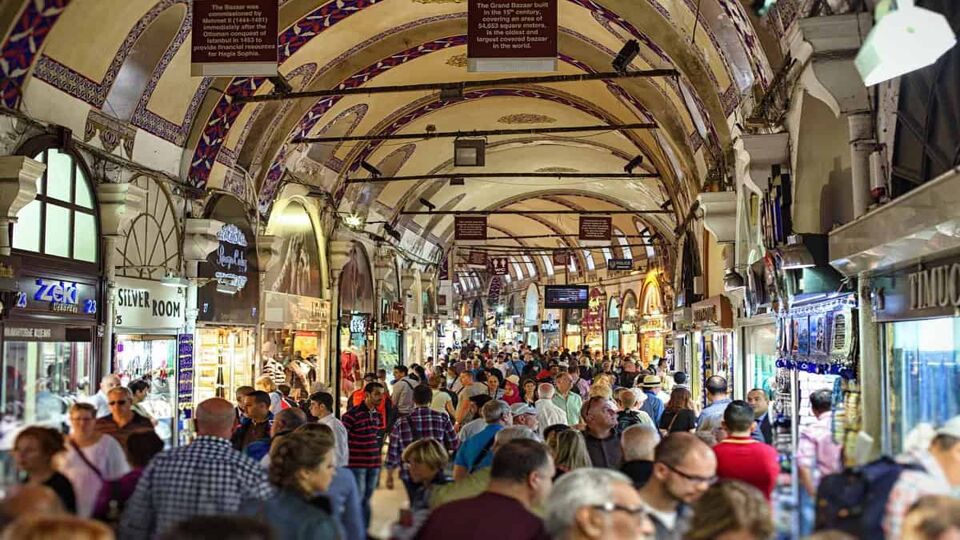 Interior walkway of covered market in Turkey with arched ceilings and shoppers passing in front of the shops lining the walls
