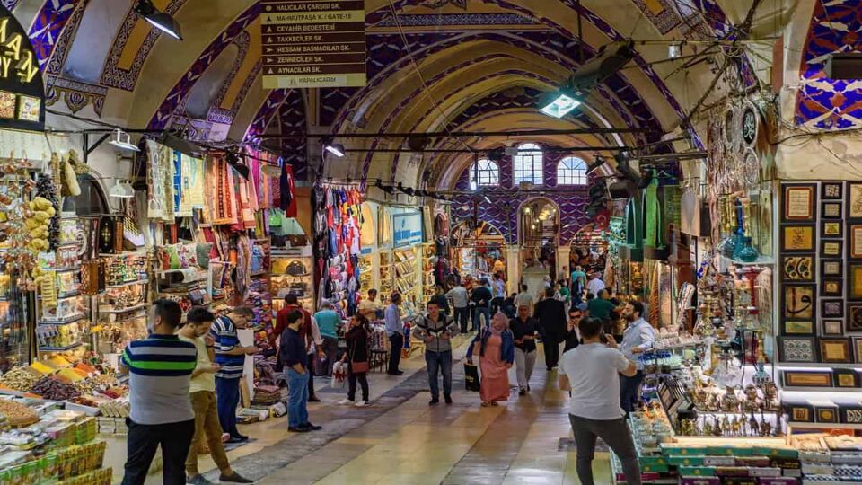 Interior walkway of covered market in Turkey with arched ceilings and shoppers passing in front of the shops lining the walls