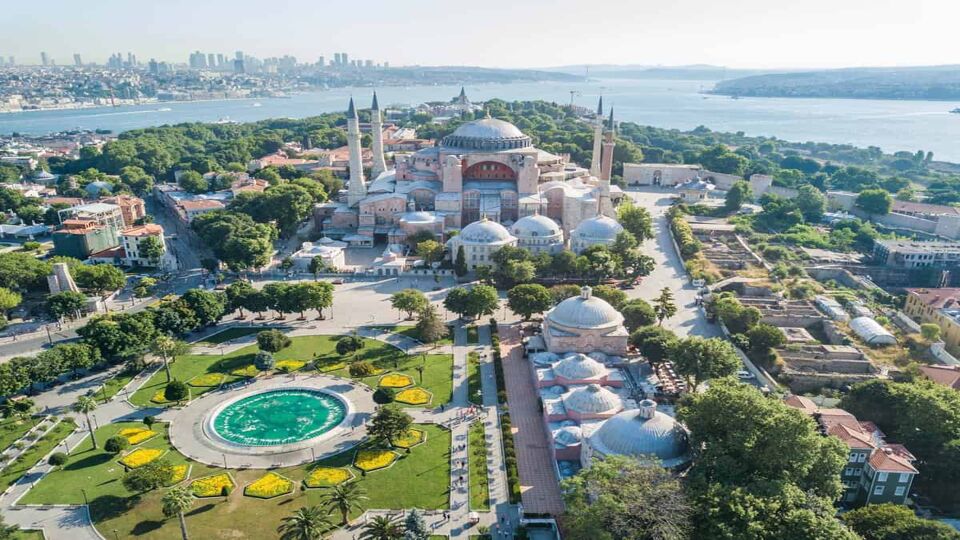 Aerial view of grand mosque surrounded by gardens and the sea in background
