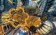 View looking up at a mosques domed ceiling with hanging chandeliers