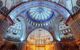 interior of a grand, domed mosque decorated with blue tiles