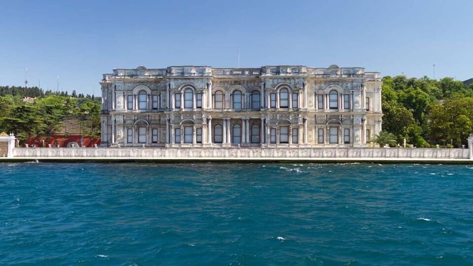 Waterfront palace flanked by trees on a sunny day