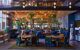 tables and chairs with tall plants in hotel lobby