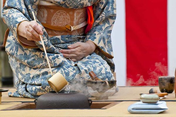 Woman ladles tea into a cup