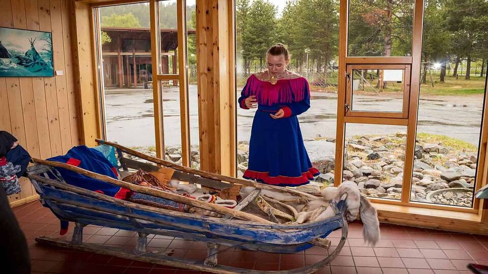 Sami woman model in front of a canoe in the Sami Museum